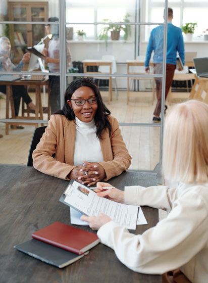 hr-specialist-holding-resume-talking-young-black-job-candidate-while-meeting-with-her-office